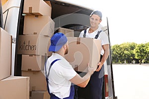 Male movers unloading boxes from van