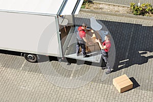 Male Movers Unloading The Cardboard Boxes Form Truck