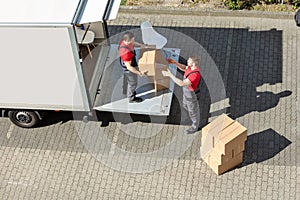 Male Movers Unloading The Cardboard Boxes Form Truck