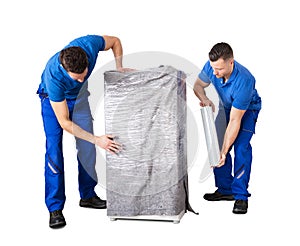 Male Movers Wrapping The Home Appliances With Plastic Wrap