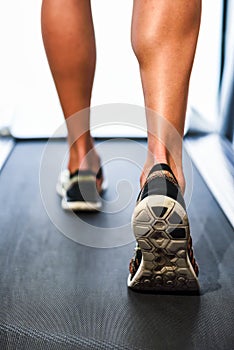 Male muscular legs running on the treadmill at the gym.