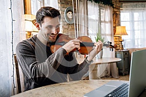 Male music teacher teaching how to play a song the violin online during a video call