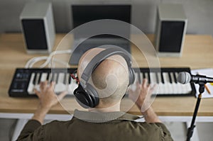 Male musician in earphones compose music on keyboards
