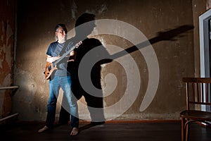 Male musician with an electric guitar on the background of an old wall