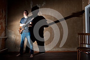 Male musician with an electric guitar on the background of an old wall