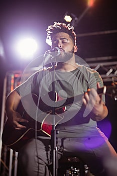 Male musician with eyes closed singing at nightclub