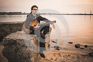 Male musician and his guitar on shore