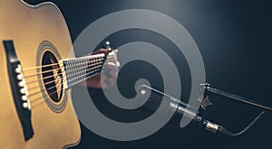 Male musician playing acoustic guitar behind microphone in recording studio.