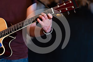 Male musician playing acoustic guitar. Guitarist plays classical guitar on stage in concert Close up