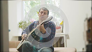 Male musician playing acoustic guitar. man playing acoustic guitar slow motion video. in the room sits on lifestyle the