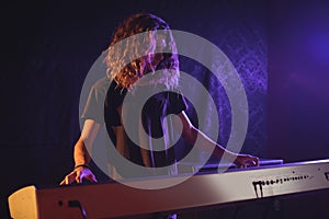 Male musician playing piano in illuminated nightclub