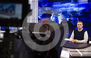 A male News anchor in a broadcast Studio reads text on a teleprompter. Camera in the TV Studio.