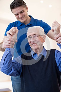 Male Nurse Assessing Senior Stroke Victim By Raising Arms