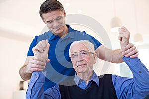 Male Nurse Assessing Senior Stroke Victim By Raising Arms