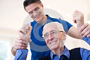 Male Nurse Assessing Senior Stroke Victim By Raising Arms photo