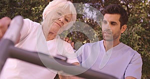 Male nurse assisting a senior woman to walk in the backyard