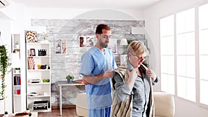 Male nurse helping senior woman getting dressed