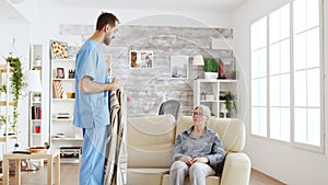 Male nurse helping senior woman getting dressed