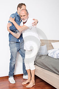 Male nurse helps man out of bed
