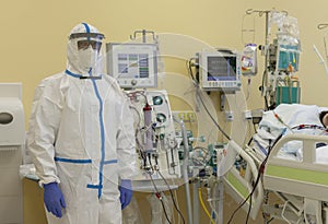 Male nurse with protective coverall clothing in intensive care unit in hospital, where are  treated patients with pneumonia caused