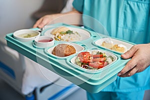 Male nurse is serving dietary meal in medical facility ward