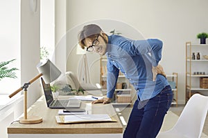 Male office worker experiences severe back pain caused by prolonged sitting in wrong position.