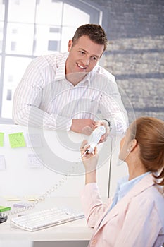 Male office worker passing phone to colleague