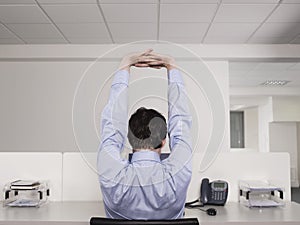 Male Office Worker Stretching At Desk photo