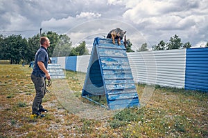 Male officer training German Shepherd dog outdoors on playground