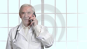 Male old doctor holding a black telephone.