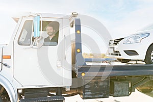 Male operator smiling and driving a tow truck