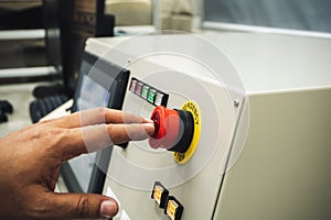 Male Operator use left hand to push emergency button to stop the machine