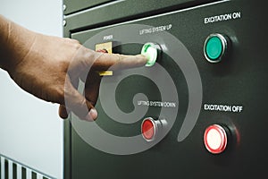 Male operator using point finger to push green button to operate machine