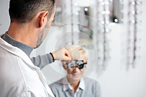 Male ophthalmologist examining mature woman at the ophthalmology clinic, determining diopter photo