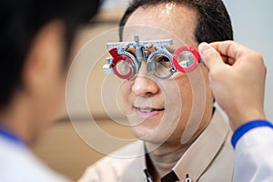 Male ophthalmologist precisely determines diopter for senior man photo