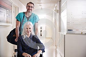 Male Orderly Pushing Senior Female Patient Being Discharged From Hospital In Wheelchair photo