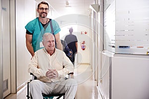 Male Orderly Pushing Senior Male Patient Being Discharged From Hospital In Wheelchair photo