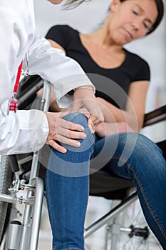 Male orthopedic doctor examining womans knee in clinic
