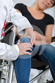 Male orthopedic doctor examining womans knee in clinic