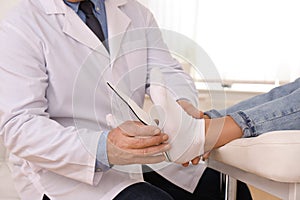 Male orthopedist fitting insole on patient`s foot in clinic