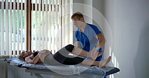 A male osteopathic masseur in a blue t-shirt kneads the girl`s hip joints, putting the damage in order. A young girl is photo