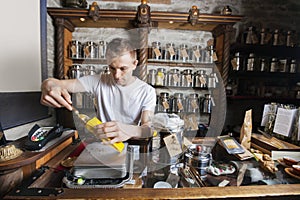 Male owner scooping ingredient into paper bag at tea store