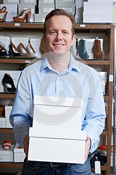 Male Owner Of Shoe Store Carrying Boxes