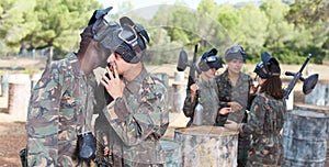 Male paintball team discussing tactic of game with opposing team