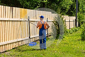 Male painter works at wooden fence