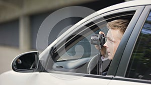 Male paparazzi sitting in car and making photos of female celebrity, sensation