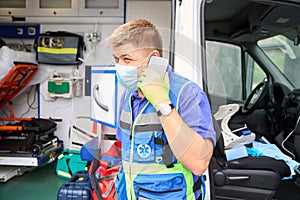 Male paramedic communicates on a mobile phone near an ambulance