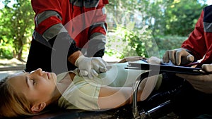 Male paramedic doing indirect heart massage, colleague using tablet for records photo