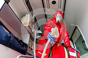 Male paramedic with face mask helping a patient with respirator in ambulance during pandemic. A portrait of paramedic sitting in