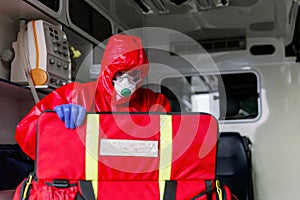 Male paramedic with face mask helping a patient with respirator in ambulance during pandemic. A portrait of paramedic sitting in